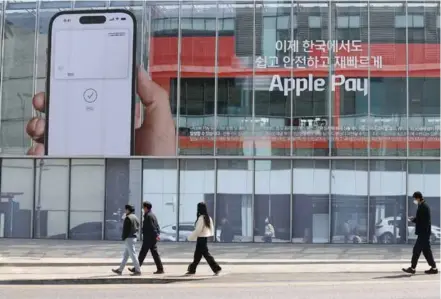  ?? Yonhap/vna Photo ?? People walk past an ad promoting Apple Pay, US tech giant Apple Inc's mobile payment service, in Seoul on the day of its launch in South Korea yesterday.