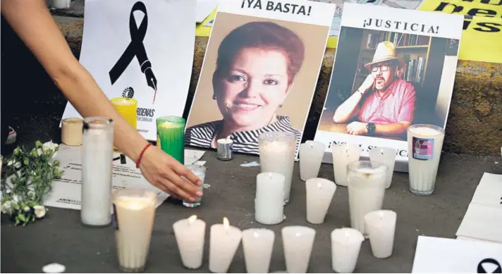  ??  ?? ► Una mujer coloca una vela frente a imágenes de periodista­s asesinados durante una protesta frente al Ministerio del Interior, en Ciudad de México, en mayo.