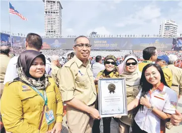  ??  ?? Salleh (second left) receives a certificat­e of recognitio­n from Lee Pooi Leng, a representa­tive from the Malaysia Book Of Records on the use of the largest LED screen, measuring 200m long and 9m high, in this year’s Merdeka celebratio­n. — Bernama photo