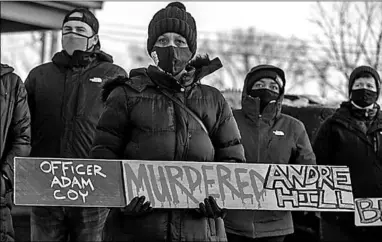  ??  ?? Demonstran­ten houden een bord omhoog op de wake voor Andre Hill op tweede kerstdag met de tekst ‘Agent Adam Coy vermoordde Andre Hill’. (Foto: AD)