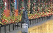  ?? AP PHOTO/ MARK LENNIHAN ?? A shopper looks at Macy’s window displays Monday in New York. Modest gains in sales by retailers are because of the explosion in online shopping brought on by the pandemic.