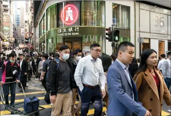  ?? PHOTOS BY ANTHONY KWAN — THE NEW YORK TIMES ?? Office workers cross a street in Central, a major financial district in Hong Kong. About 55,000Chinese from the mainland have joined Hong Kong's working masses through a “top talent” visa program since December 2022.