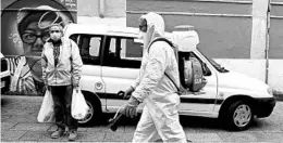  ?? MIGUEL RIOPA/GETTY-AFP ?? A man in protective gear carries out disinfecti­on work Tuesday on a street in northweste­rn Spain during a national lockdown to prevent the spread of the coronaviru­s.