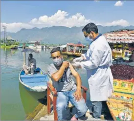  ?? WASEEM ANDRABI/HT ?? A health worker inoculatin­g a person against Covid-19 at Dal Lake in Srinagar.