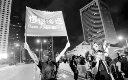  ?? AP ?? A demonstrat­or holds a sign reading ‘Back away slowly’ to encourage other demonstrat­ors to leave, near the Chinese Liaison Office in Hong Kong yesterday.