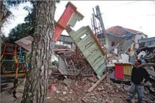  ?? ?? A man stands beside damaged houses following an earthquake in Cianjur on Monday.