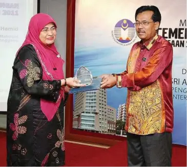  ??  ?? Exemplary teacher: Sharifah Afidah receiving the award from Sufa’at during the ceremony.