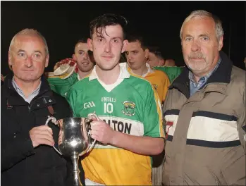  ??  ?? Stephen Watchorn receives the cup from Murt Joyce (sponsor) as Seamus Whelan (Enniscorth­y District Secretary) looks on.