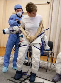  ??  ?? NASA flight engineer Anne Mcclain (below) is helped into her Russian Sokol suit as she prepares for a Soyuz launch to the Internatio­nal Space Station, in 2018.