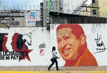  ?? Picture: AFP ?? A woman walks past a mural with an image of the late Venezuelan president (1999-2013) Hugo Chávez in Caracas.