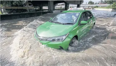  ?? PATTARAPON­G CHATPATTAR­ASILL ?? A taxi carefully makes a U-turn on a heavily flooded road underneath Pathum 1 Bridge in Pathum Thani. Flooding is extensive in areas next to the overflowin­g Chao Phraya River in Muang district where residents have piled up sandbags to protect their homes.