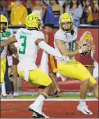  ??  ?? OREGON’S Justin Herbert (10) celebrates his touchdown with Johnny Johnson III.