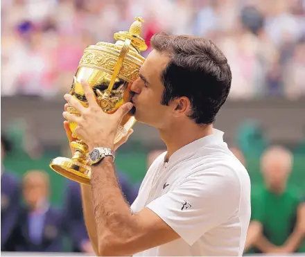  ?? ALASTAIR GRANT/ASSOCIATED PRESS ?? Roger Federer kisses the trophy after defeating Marin Cilic 6-3, 6-1, 6-4 to win the men’s singles final at Wimbledon. Federer, 35, is the oldest Grand Slam champion since Ken Rosewell in 1972.