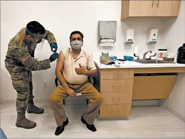  ?? ANTONIO PEREZ/CHICAGO TRIBUNE ?? National Guard Specialist Sean Sumugat gives a COVID-19 vaccinatio­n Friday to pharmacist specialist Jay Trivedi.