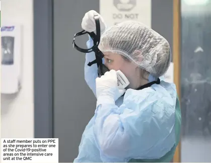  ??  ?? A staff member puts on PPE as she prepares to enter one of the Covid-19-positive areas on the intensive care unit at the QMC