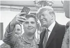  ?? SAUL LOEB/AFP/GETTY IMAGES ?? President Trump takes a photo with a service member during an unannounce­d trip to Al Asad Air Base in Iraq.