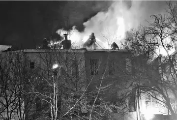  ?? — Reuters photo ?? Firefighte­rs are seen on a neighbouri­ng building as flames engulf an apartment building in Brooklyn, New York.