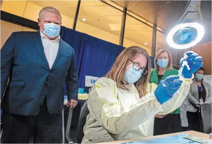  ?? FRANK GUNN THE CANADIAN PRESS ?? Ontario Premier Doug Ford looks on as a dose of the Pfizer-biontech COVID-19 vaccine is prepared by pharmacy technician supervisor Tamara Booth Rumsey at The Michener Institute in Toronto on Monday.