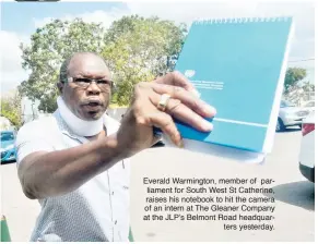  ??  ?? Everald Warmington, member of parliament for South West St Catherine, raises his notebook to hit the camera of an intern at The Gleaner Company at the JLP’s Belmont Road headquar
ters yesterday.