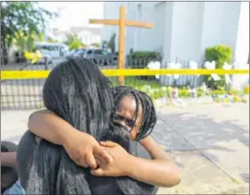  ?? CURTIS COMPTON / CCOMPTON@AJC.COM ?? Kearston Farr, who attended worship services at the “Mother” Emanuel A.M.E. Church, hugs her 5-year-old daughter Taliyah who begins to weep while visiting the memorial in front of the church on Friday, in Charleston, S.C.