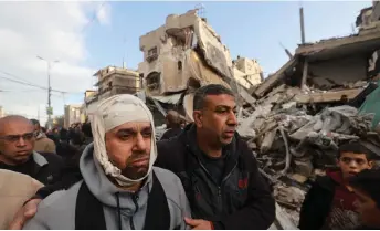  ?? — AFP photo ?? Wounded Palestinia­n Nidal al-Gharib, who lost his wife and daughter, walks past his neighbours’ house destroyed by Israeli bombing in Rafah in the southern Gaza Strip.