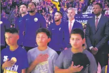  ?? Santiago Mejia / The Chronicle ?? The Warriors, as usual, stand for the national anthem before their first preseason game with the Nuggets at Oracle Arena.