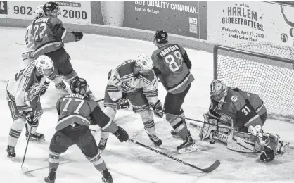  ?? JASON SIMMONDS/JOURNAL PIONEER ?? Summerside Western Capitals forward Nick Reeves, 77, attempts to bang home a rebound past Grand Rapids goaltender Tyriq Outen while battling with defenceman Evan Jackson, 88, during Thursday night’s Maritime Junior Hockey League game at Eastlink Arena. Also following the play closely are the Caps’ Riley MacDougall, 15, and Marc-Andre LeCouffe, 42, along with the Rapids’ Matt MacKay, 77, and Ronan Rheaume, 22. The Caps won the game 3-2 on a third-period goal by Reeves.