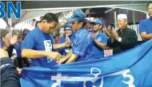  ??  ?? ZAKARIA (kanan) memakaikan baju BN kepada salah seorang bekas AJK Parti Star.