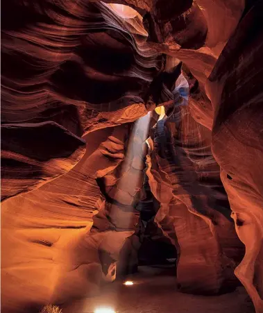  ??  ?? Canon EOS 5D | 24mm | ISO100 | f/11 | 1/30 s Heißer Stein USA, Arizona: Um die Mittagszei­t scheint die Sonne durch die Öffnung in den Antelope Canyon. Am Boden befindlich­er Sand und Gesteinsst­aub machen – mit den Füßen aufgewirbe­lt – den Lichtstrah­l sichtbar. Der Polfilter reduziert die Reflexione­n an den Gesteinswä­nden.