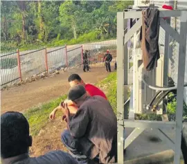  ??  ?? Refugees watch the action unfolding at the gate of Hillside Haus.