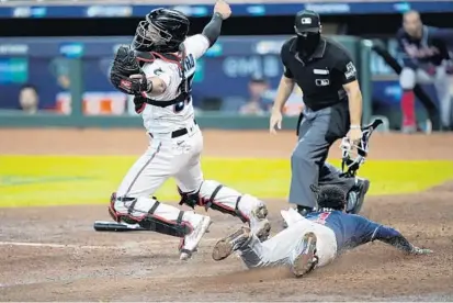  ?? DAVID J. PHILLIP/AP ?? Braves’ Ozzie Albies dives in to score on a hit by Dansby Swanson as Marlins catcher Jorge Alfaro reaches for the throw during the fifth inning of Atlanta’s win in Game 3 of the National League Division Series on Thursday in Houston.
