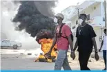 ?? ?? DAKAR: Opposition supporters walk next to a burning barricade during demonstrat­ions called by the opposition parties on February 4, 2024. — AFP