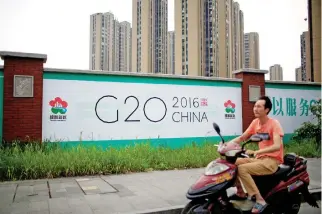  ??  ?? BUILDING HOPE: A man rides an electronic bike past a billboard for the G20 summit in Hangzhou, Zhejiang province, China. (Reuters)