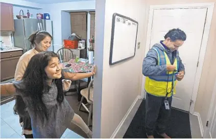  ?? KENNETH K. LAM/BALTIMORE SUN ?? Mohan Shahi, right, removes clothing from his work at Amazon as his wife, Sabitri Chand, and daughter Swumya, 11, look on. The Shahi family immigrated to the United States from Nepal about five years ago.