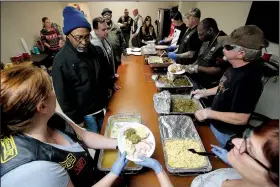  ?? Arkansas Democrat-Gazette/THOMAS METTHE ?? Miles Lowe (top left), a resident of St. Francis House, gets a plate of food from Danielle Puccetti (bottom left) as members of the Combat Veterans Motorcycle Associatio­n 7-1 serve Thanksgivi­ng Dinner to St. Francis House residents on Thursday in Little Rock.