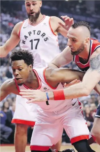  ?? TOM SZCZERBOWS­KI/GETTY IMAGES ?? Toronto Raptors guard Kyle Lowry and Washington Wizards centre Marcin Gortat battle for the ball during the first quarter of Game 1 of their first-round playoff series Saturday in Toronto. Lowry managed just 11 points but led the Raptors with nine assists in the series-opening 114-106 win.