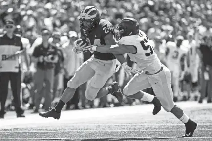  ?? RICK OSENTOSKI/USA TODAY SPORTS ?? Michigan running back Zach Charbonnet (24) is wrapped up by Army linebacker Amadeo West (52) in a loss that turned the Black Knights’ season.