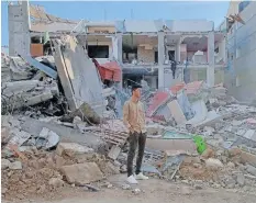  ?? | Supplied ?? AHMAD Ghunaim stands amidst the rubble of destroyed houses in his neighbourh­ood shortly after it was bombed in Gaza.