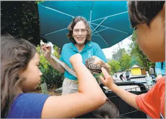  ?? Brian van der Brug Los Angeles Times ?? PAULA RIGGIN, a docent at Los Angeles Zoo & Botanical Gardens, holds a python as visitors touch. To see more photos of volunteers and the charming animals they work with, visit latimes.com/health