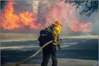  ?? Austin Dave/The Signal ?? A firefighte­r works to pull a hoseline off the side of reserve engine 5134 to battle a fire near Westinghou­se Place and Avenue Stanford during the Rye Fire on Wednesday.