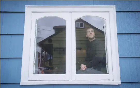  ?? PHOTOS: DARRYL DYCK / THE CANADIAN PRESS ?? David Repa gazes out a window at his home in Powell River, B.C. Repa moved from Vancouver last year when he realized he would never be able to afford a house in the city. In Powell River, he has a home that is a block away from the ocean and has a...