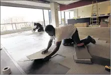  ??  ?? Corey Jackson installs carpet tiles in the new all-inclusive Redbird Club at the Downtown park.