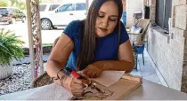  ?? Kirk Sides/Staff photograph­er ?? Erika Gonzalez uses a wood-burning pen to burn a design onto the lid of a custom-built charola.