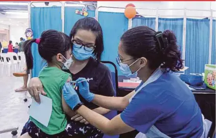  ?? PIC BY AZIAH AZMEE ?? A mother helping her daughter receive a dose of the Covid-19 vaccine at the Da Men Mall Off-Site Vaccinatio­n Centre in Subang Jaya yesterday.