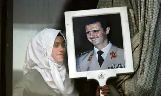  ?? Omar Sanadiki/Reuters ?? Refugiada síria que fugiu para o Líbano segura retrato do ditador sírio Bashar al-Assad