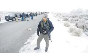  ??  ?? A man stands guard after members of the “3% of Idaho” group and other organizati­ons arrive at the wildlife refuge Saturday. Rick Bowmer, The Associated Press