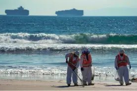  ?? ROBERT HANASHIRO/USA TODAY ?? A cleanup crew looks for oil along Huntington Beach on Tuesday after a spill from a pipeline off Southern California’s coast.