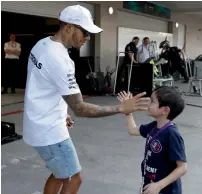  ?? AP ?? Mercedes driver Lewis Hamilton high fives a young fan at the Hermanos Rodriguez racetrack in Mexico City. —