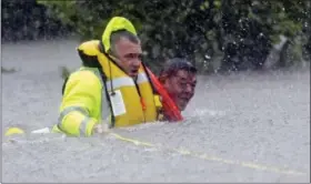  ?? DAVID J. PHILLIP — THE ASSOCIATED PRESS ?? Wilford Martinez, right, is rescued from his flooded car by Harris County Sheriff’s Department Richard Wagner along Interstate 610 in floodwater­s from Tropical Storm Harvey on Sunday in Houston, Texas.