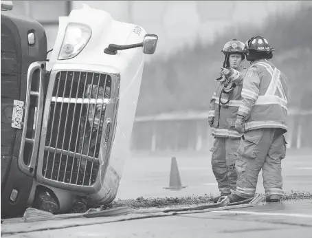  ?? DAX MELMER ?? Emergency responders look over the scene of a transport truck that rolled over on an on ramp to Highway 401 from Highway 3 in August.